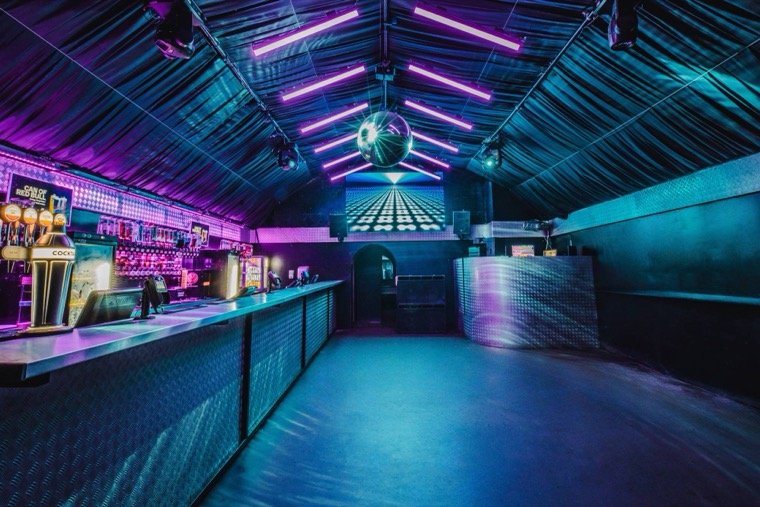 FIRE Lounge — a neon-lit room with a long bar, disco ball and big screen